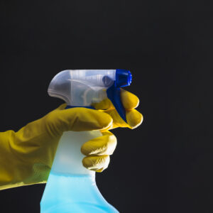 mano-del-conserje-con-guantes-amarillos-sosteniendo-la-botella-del-aerosol